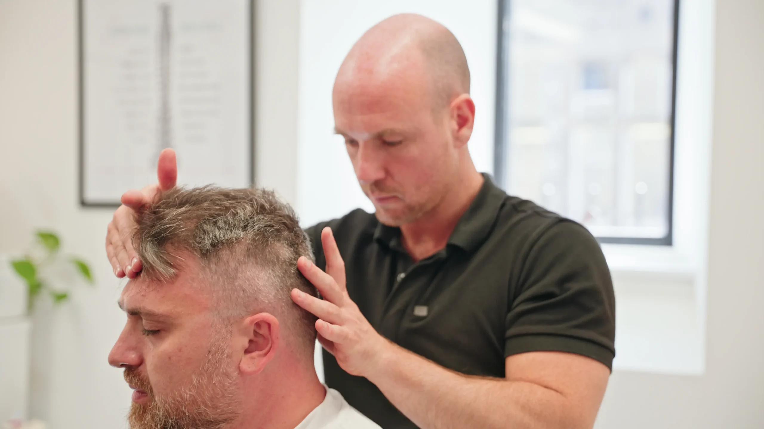 Chiropractor assessing jaw, neck and head pressure during consultation in Edinburgh