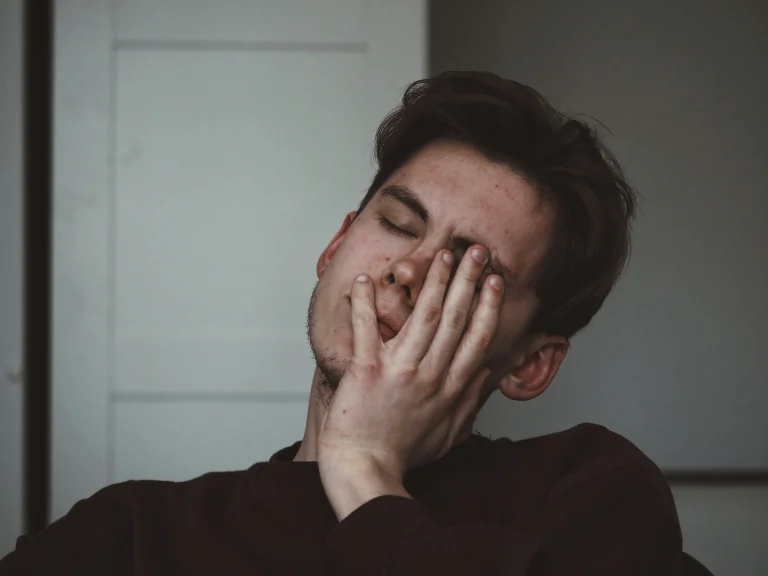 Man sitting at a desk holding his head due to constant daily headaches