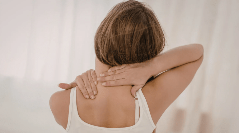 Woman with hands on neck, experiencing neck tension related to migraines and jaw tightness.