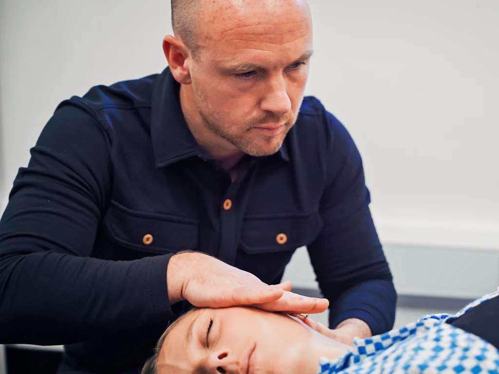 Chiropractor Paul Holmes using a gentle, low-force cranial technique on a relaxed patient in Edinburgh